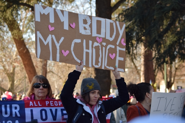 Image of a pro-choice rally. A young woman holds up a handmade sign that reads "My body my choice."