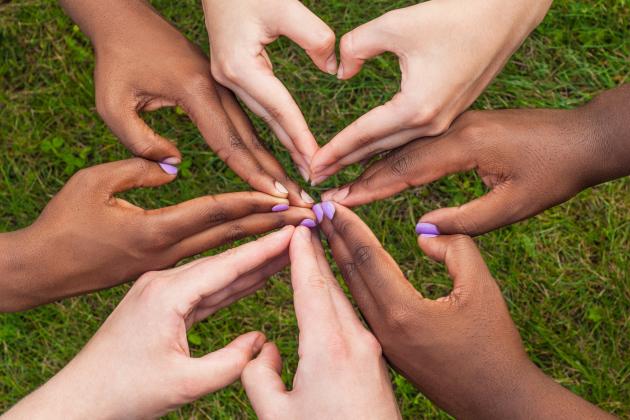 Diverse hands forming hearts together