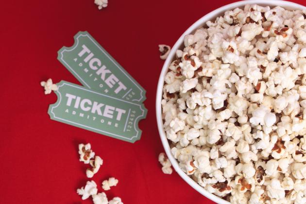 Two movie tickets beside a bucket of popcorn