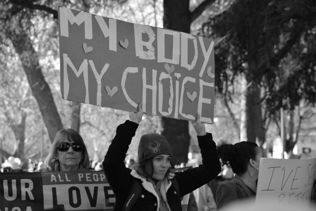 Black and white photo of woman holding up sign during protest that says My Body My Choice