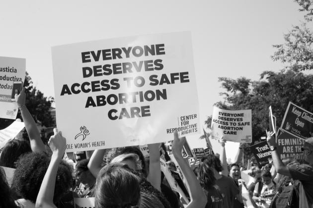 Person holding a sign saying everyone deserves access to safe abortion care