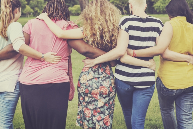 Image of Group of people from behind holding each other with linked arms