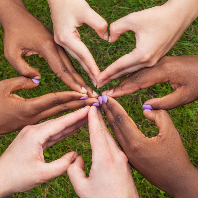 Diverse hands forming hearts together