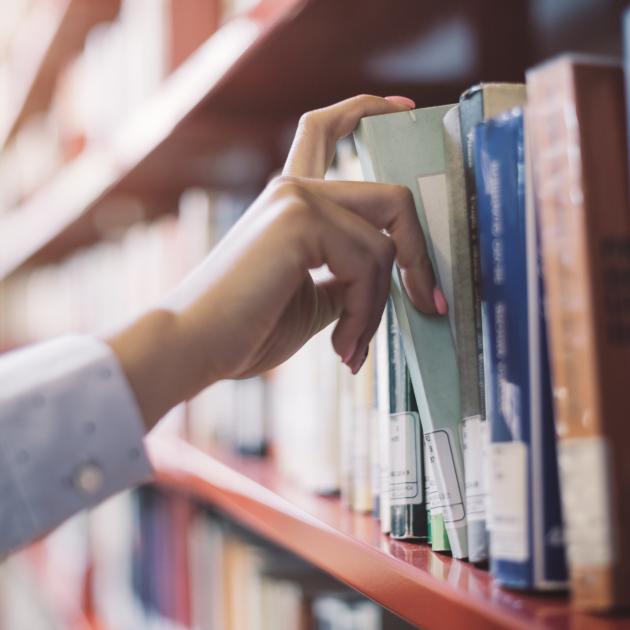 Hand removing a library book from the shelf