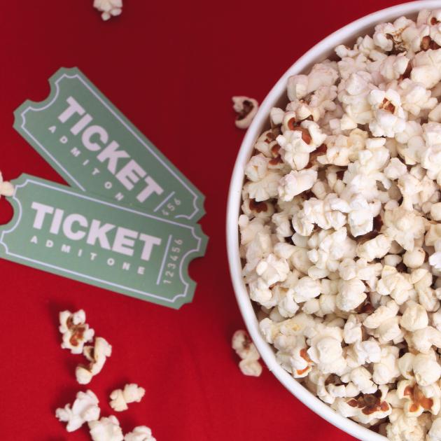 Two movie tickets beside a bucket of popcorn