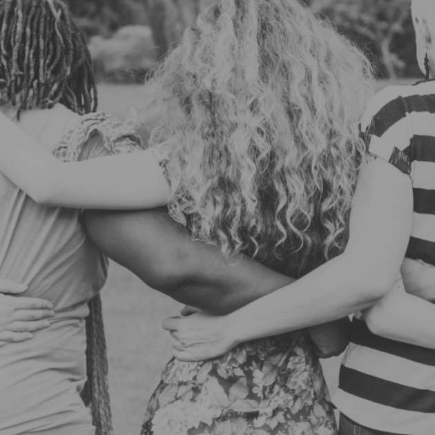 Black and white photo of a five people facing away from the camera, in a linear embrace