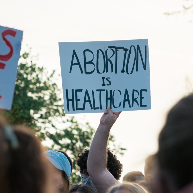 People at a pro-choice rally. Someone holds a sign that says "abortion is healthcare"