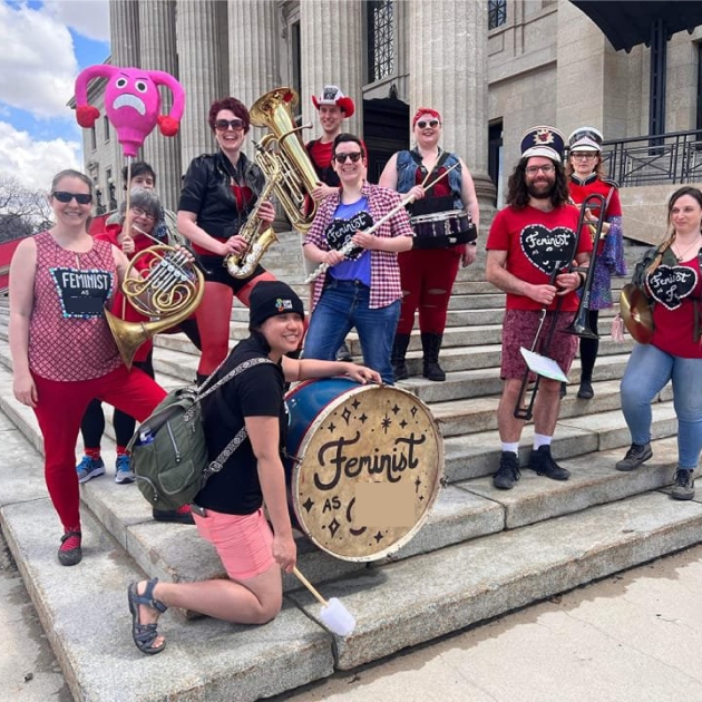 Group picture of marching band members holding their instruments on steps outside