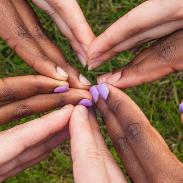 The hands of several individuals connected in a symbol of support.